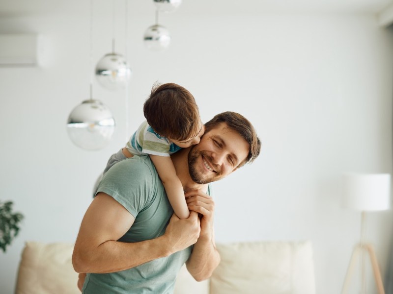 Ein liebevoller Vater trägt seinen kleinen Sohn huckepack.