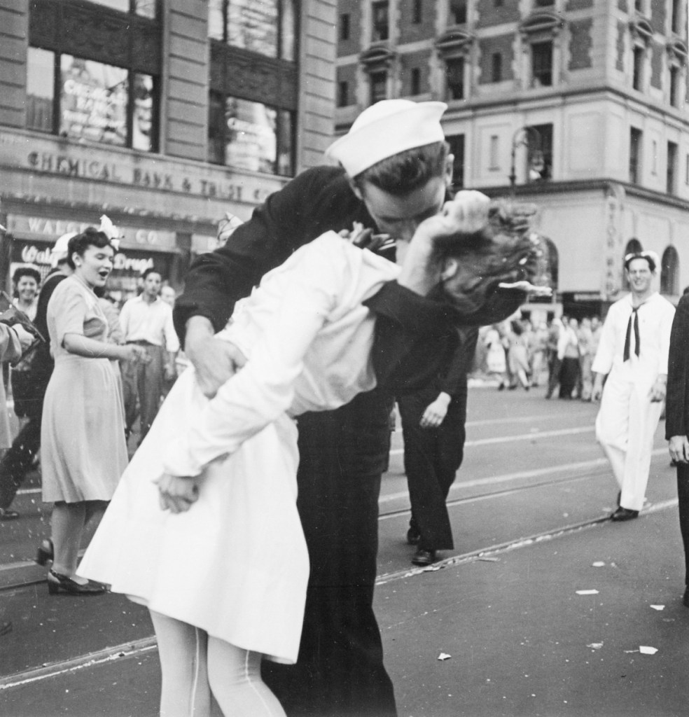 Ein historisches Foto in schwarzweiß von einer Frau, die auf dem Times Square, New York, von einem Soldaten geküsst wird.