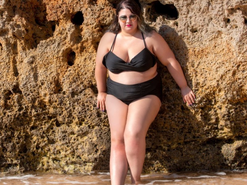 Eine vollschlanke Frau im Bikini an einem Strand.