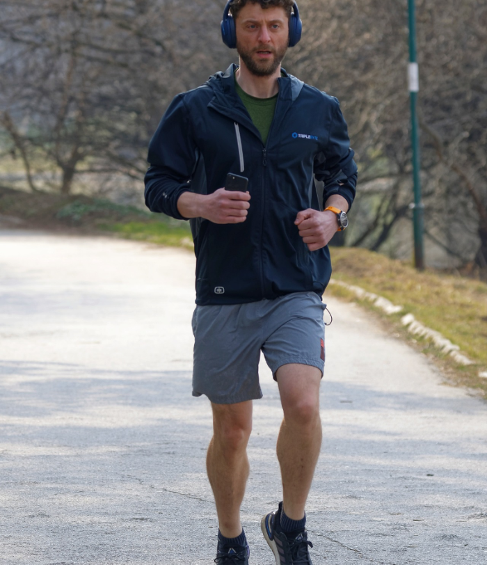 Ein Mann mit Kopfhörern und kurzer Hose joggt durch einen Park