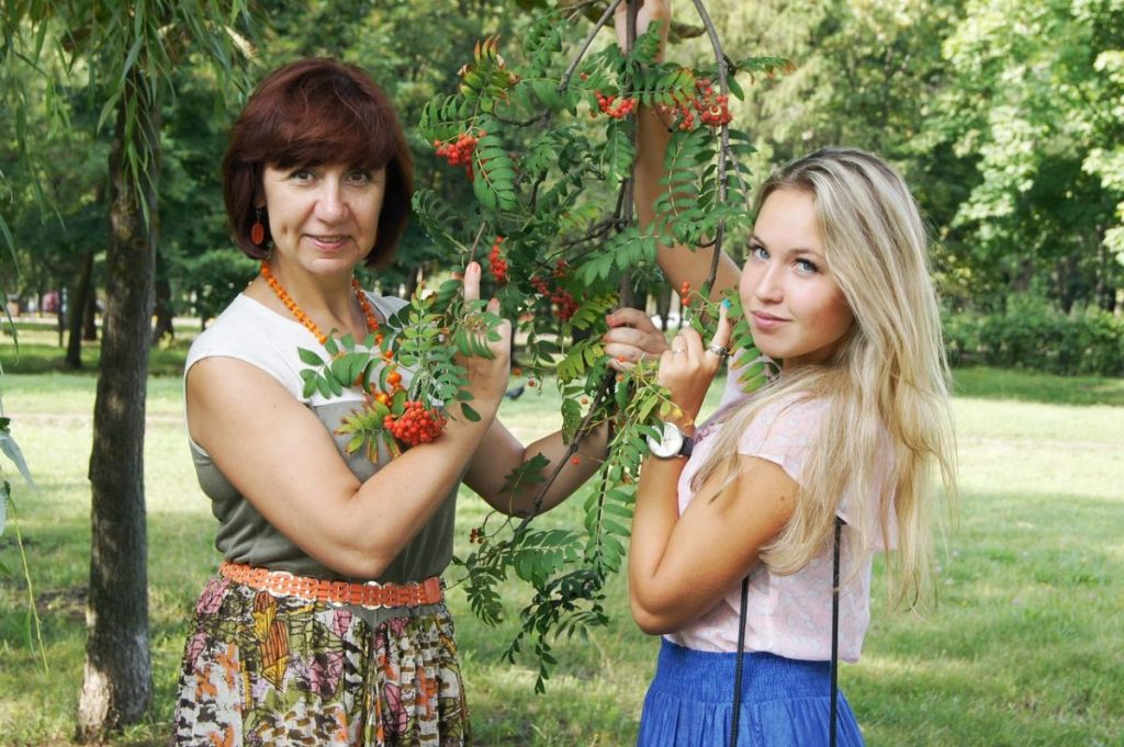 Eine Mutter hält mit ihrer blonden Tochter einen geflochtenen Kranz in den Händen.