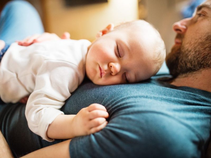 Ein Baby schläft auf dem Bauch seines Vaters.